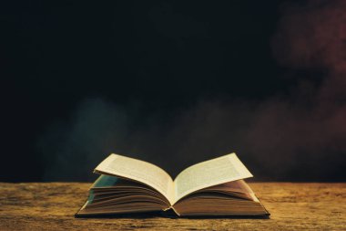 Meşe ahşap bir masa üzerine eski kitap. Arka plan mavi ve kırmızı duman.