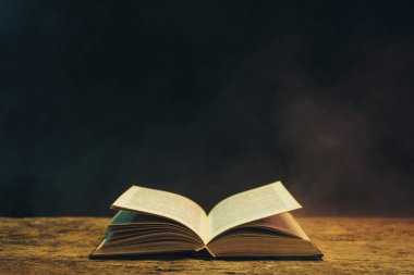 Meşe ahşap bir masa üzerine eski kitap. Arka plan mavi ve kırmızı duman.