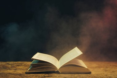 Meşe ahşap bir masa üzerine eski kitap. Arka plan mavi ve kırmızı duman.