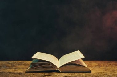 Meşe ahşap bir masa üzerine eski kitap. Arka plan mavi ve kırmızı duman.
