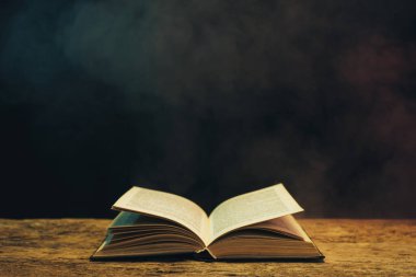 Meşe ahşap bir masa üzerine eski kitap. Arka plan mavi ve kırmızı duman.