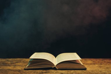 Meşe ahşap bir masa üzerine eski kitap. Arka plan mavi ve kırmızı duman.