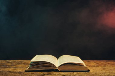 Meşe ahşap bir masa üzerine eski kitap. Arka plan mavi ve kırmızı duman.