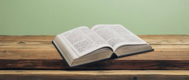 Kutsal İncil 'i eski bir meşe ağacından masanın üzerinde aç. Yeşil duvar arka planı.