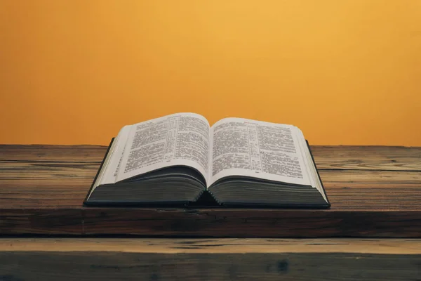 Die Bibel Auf Einem Alten Eichentisch Aufschlagen Orangefarbener Hintergrund — Stockfoto