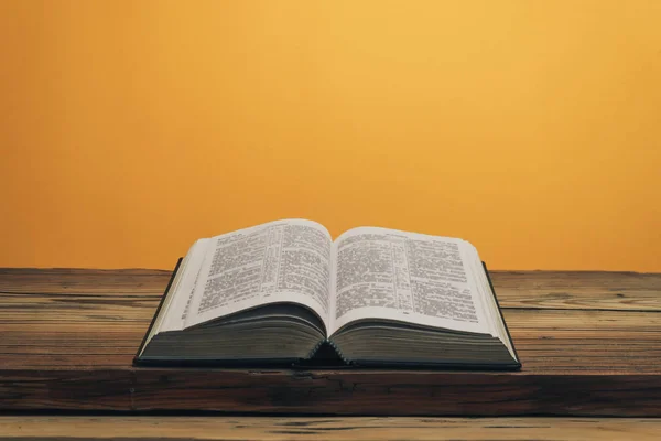 Öppna Bibeln Ett Gammalt Träbord Orange Vägg Bakgrund — Stockfoto