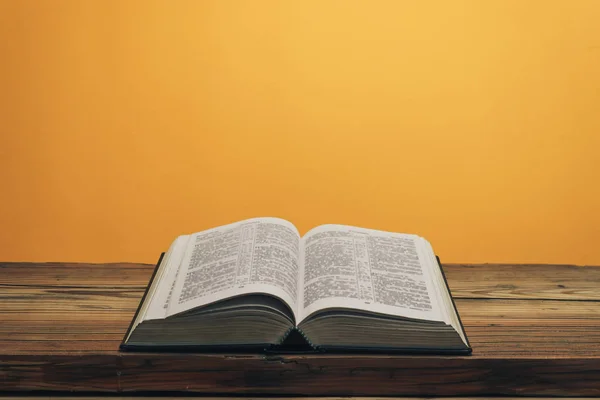 Nyissa Bibliát Egy Régi Tölgyfa Asztalon Narancs Fal Háttér — Stock Fotó