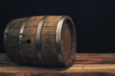 Eski bir meşe masasında ahşap varil. Arkasında siyah arka plan.