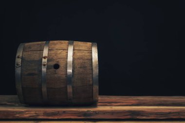 Eski bir meşe masasında ahşap varil. Arkasında siyah arka plan.