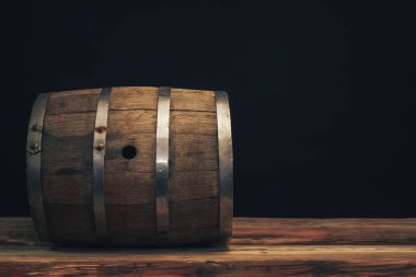 Eski bir meşe masasında ahşap varil. Arkasında siyah arka plan.