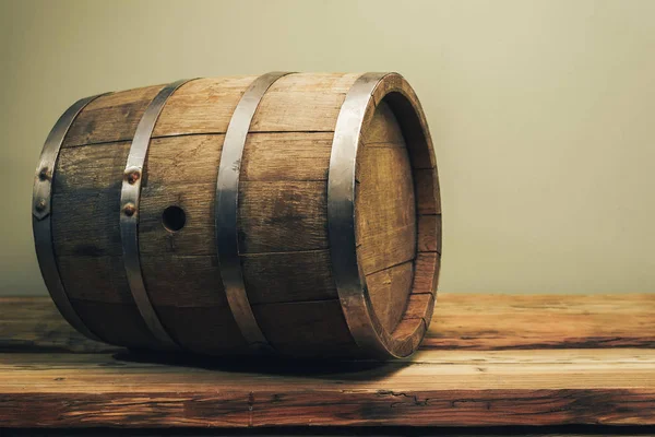 Eski bir meşe masasında ahşap varil. Arkasında yeşil arka plan.