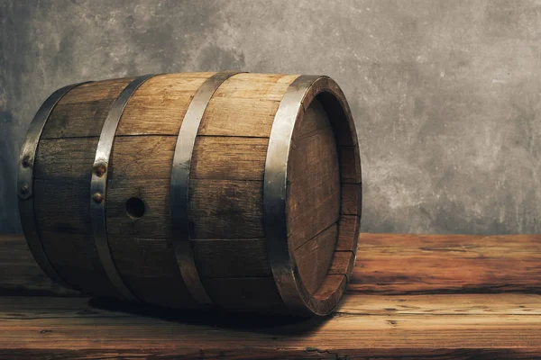 Wooden barrel on a old oak table. Gray background behind.