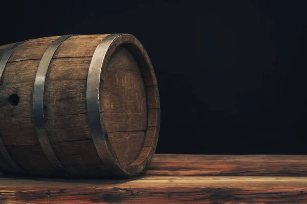 Wooden barrel on a old oak table. Black background behind.