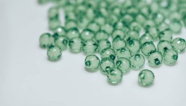 Beyaz arka planda yeşil cam boncuk. Makro görünümü.