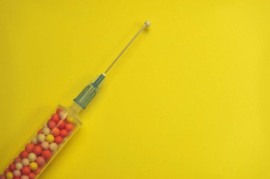 Şırınga sarı bir arka plan üzerinde renkli nano topları ile dolu. Yenilikçi tıbbi konsept. 