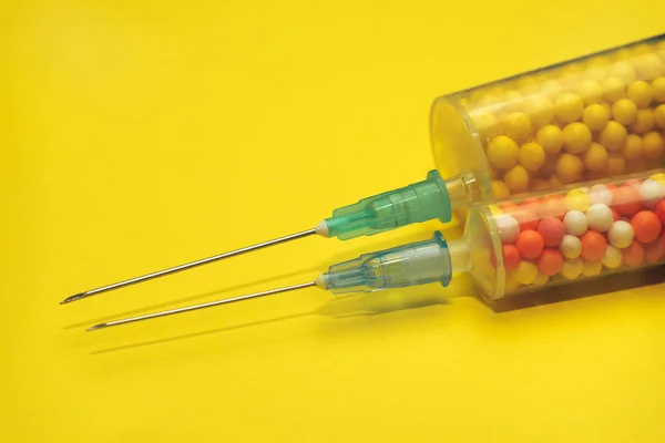 Dwie Strzykawki Wypełnione Kolorowymi Nano Kulki Żółtym Tle Innowacyjna Koncepcja — Zdjęcie stockowe