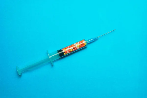 青い背景にカラフルなナノボールで満たされた注射器 革新的な医療コンセプト — ストック写真