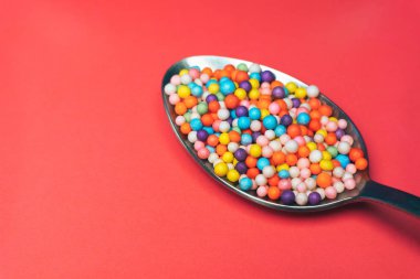 kırmızı bir arka plan üzerinde kaşık renkli preparatlar (vitaminler, boyalar, lezzet arttırıcılar, besin takviyeleri, yenilikçi teknoloji, şeker tatlılar).