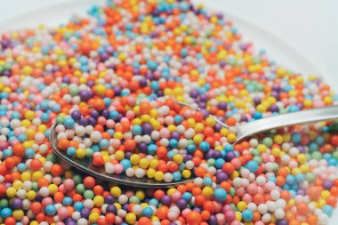 Turuncu bir zemin üzerinde beyaz tabak ve kaşık renk hazırlama (vitaminler, boyalar, lezzet artırıcılar, beslenme takviyeleri, yenilikçi teknolojiler, şeker tatlılar). Kapat.