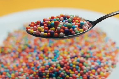 Turuncu bir zemin üzerinde beyaz tabak ve kaşık renk hazırlama (vitaminler, boyalar, lezzet artırıcılar, beslenme takviyeleri, yenilikçi teknolojiler, şeker tatlılar). Kapat.