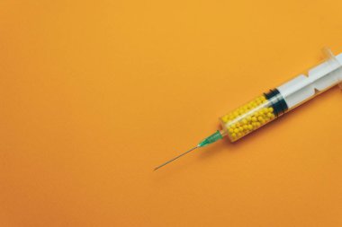 Kırmızı arka planda renkli ilaçlar (vitaminler, boyalar, aroma arttırıcılar, besin takviyeleri, yenilikçi teknolojiler) ile şırınga.