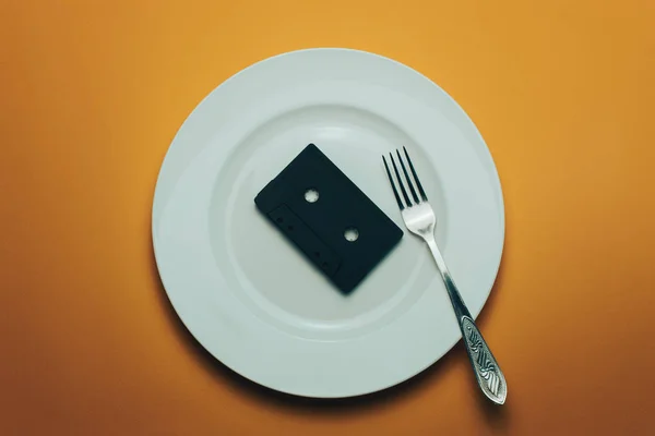 Schwarze Klassische Magnetkassette Weißem Teller Mit Orangefarbenem Besteck — Stockfoto