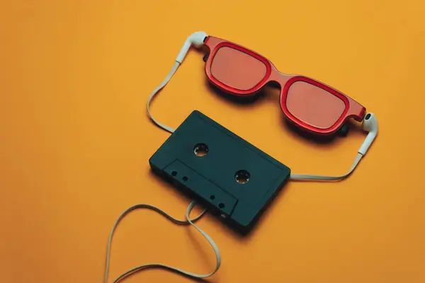 주황색 배경에 빨간색 검은색 마그네틱 카세트 테이프 헤드폰 — 스톡 사진
