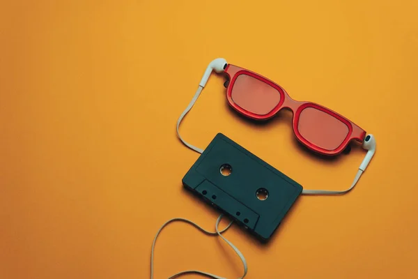 Rot Verglastes Schwarzes Magnetband Und Weiße Kopfhörer Auf Orangefarbenem Hintergrund — Stockfoto
