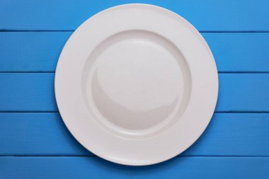 Mavi ahşap arka planda beyaz tabak. Üst görünüm.