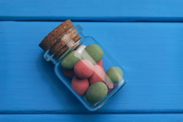 Kleine Fles Veelkleurige Pinda Chocolade Ijsvorming Blauwe Houten Tafel Achtergrond — Stockfoto