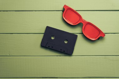 Yeşil ahşap masa arka plan üzerinde kırmızı camlı, siyah manyetik kaset.