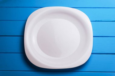 Mavi ahşap bir arka planda beyaz tabak..