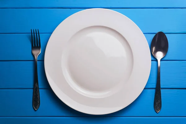 Weißer Teller Und Eine Gabel Mit Einem Löffel Auf Blauem — Stockfoto