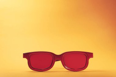 Turuncu masa arka planı üzerinde kırmızı gözlükler. Yaz konsepti.