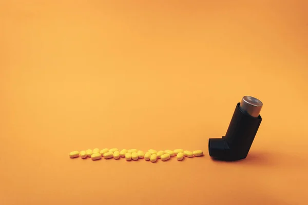 주황색 배경에 노란색 비타민 강화제 보충제 에어로졸 급여를 함유한 흡입기 — 스톡 사진