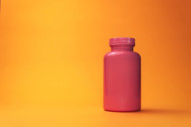 Turuncu bir arka plan üzerinde haplar için pembe şişe.