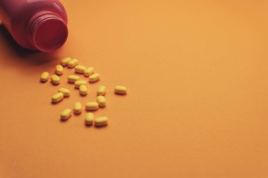 Turuncu bir arka plan üzerinde güzel pembe şişe ve sarı haplar. 