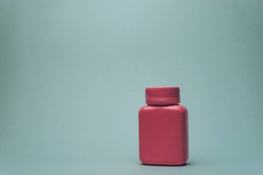 Gri arka planda haplar için pembe şişe.