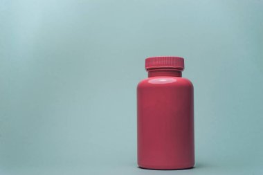 Gri arka planda haplar için pembe şişe.