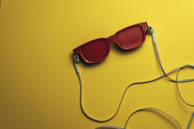 Güzel sarı arka plan üzerinde kırmızı camlı, siyah manyetik kaset ve beyaz kulaklıklar.