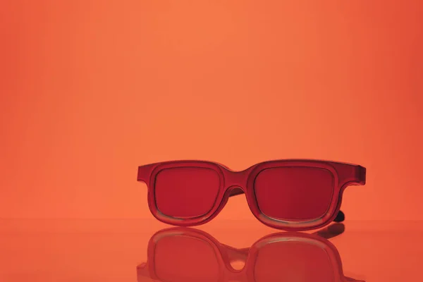 Czerwone Okulary Szklanym Stole Koralowe Pomarańczowe Tło Koncepcja Letnia — Zdjęcie stockowe