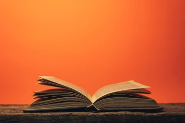 Eski bir meşe ahşap masa ve mercan turuncu duvar arka plan arkasında eski kitap.