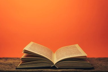 Eski bir meşe ahşap masa ve mercan turuncu duvar arka plan arkasında eski kitap.