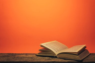 Eski bir meşe ahşap masa ve mercan turuncu duvar arka plan arkasında eski kitap.