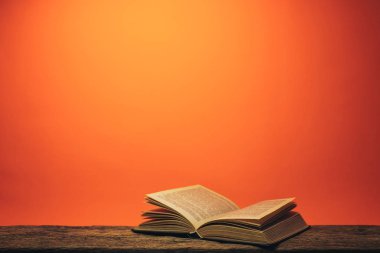 Eski bir meşe ahşap masa ve mercan turuncu duvar arka plan arkasında eski kitap.