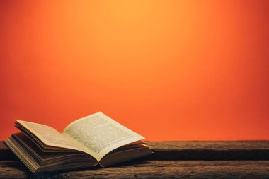 Eski bir meşe ahşap masa ve mercan turuncu duvar arka plan arkasında eski kitap.