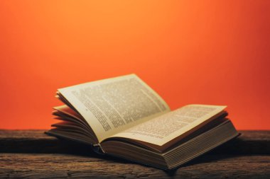 Eski bir meşe ahşap masa ve mercan turuncu duvar arka plan arkasında eski kitap.