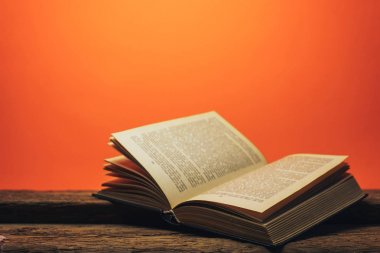 Eski bir meşe ahşap masa ve mercan turuncu duvar arka plan arkasında eski kitap.