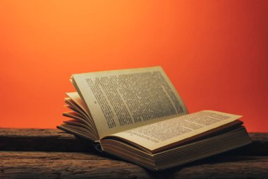 Eski bir meşe ahşap masa ve mercan turuncu duvar arka plan arkasında eski kitap.