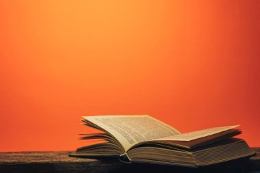 Eski bir meşe ahşap masa ve mercan turuncu duvar arka plan arkasında eski kitap.